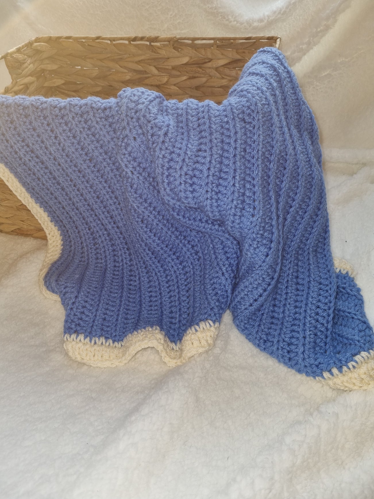 Crochet blue blanket, with a cream edge.